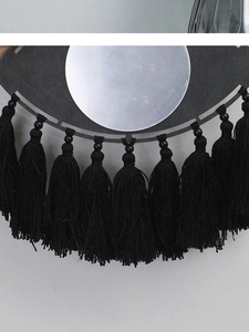 Détail de la décoration murale bohème en forme d'œil avec miroir et franges noires