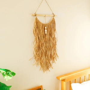 Detail of bohemian raffia wall hanging with wooden beads and fringes for home decor