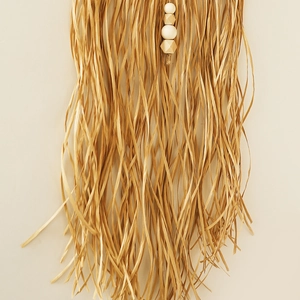 Detail of bohemian raffia wall hanging with wooden beads and handmade fringe texture