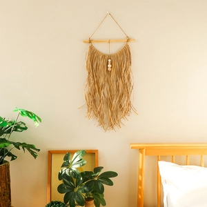 Close-up of bohemian wall hanging with natural raffia fringe and wooden bead accents