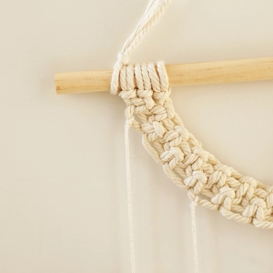 Close-up of bohemian macrame wall hanging showing intricate cotton weave and wood grain