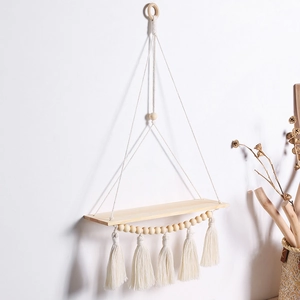 Detail of bohemian handmade wooden wall shelf with white cotton ropes and tassels