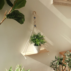 Detail of macrame plant shelf with evil eye beads and natural wood board on wall