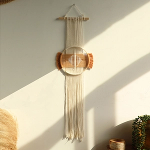 Detail of bohemian hand-woven tapestry with wood ring and orange geometric pattern