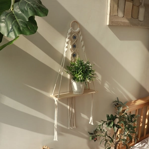 Bohemian handmade macrame wall shelf with evil eye charms and a natural wooden plank