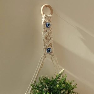Detail of bohemian handmade cotton rope plant hanger with evil eye beads and wood ring