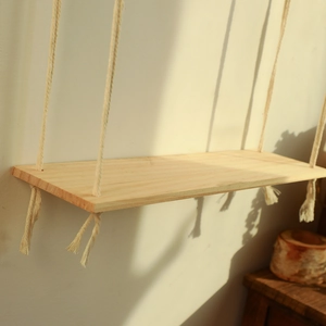 Close-up of bohemian wall hanging shelf featuring natural wood grain and cotton rope tassels