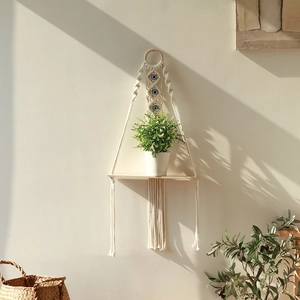 Detail of bohemian handmade macrame wall shelf with evil eye beads and wood base