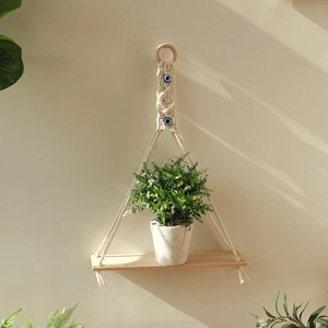 Detail of bohemian woven macrame wall shelf with evil eye beads and natural wood board
