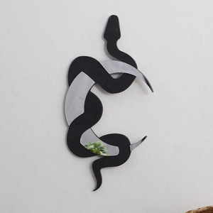 Detail of bohemian wood snake and crescent moon mirror wall decor with matte black finish