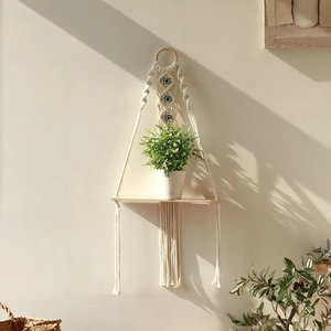 Detail of macramé wall shelf with woven evil eye beads and natural wooden board