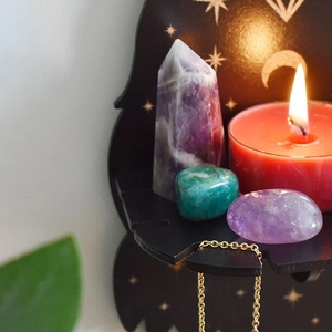 Detail of wooden altar shelf with gold moon patterns, crystals and a red candle