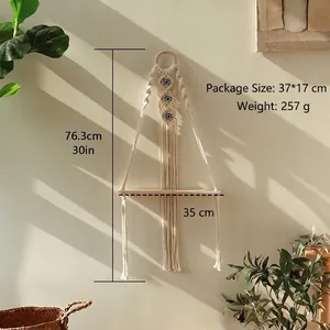 Detail of bohemian woven macrame wall shelf with evil eye beads and natural wood base