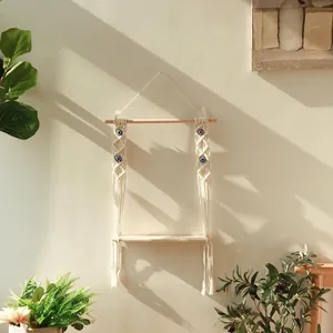 Detail of handmade boho wall shelf with cotton rope weaving and blue eye ornament