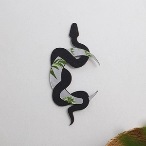 Detail showing the black snake wooden frame with crescent moon mirror on a white wall