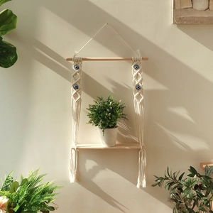 Detail of bohemian woven wall shelf with blue evil eye beads and hanging plant decor