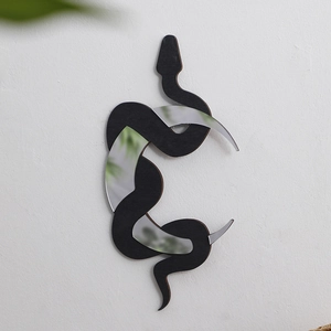 Detail of bohemian wooden snake wall mirror with crescent accents on a white wall