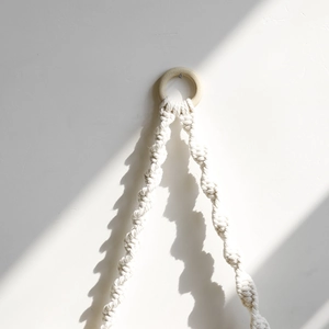 Detail of bohemian handmade cotton woven wall hanging with wooden ring and natural light