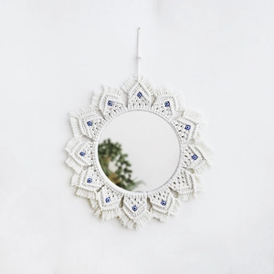 Close-up of handmade bohemian woven mirror with evil eye bead charms and cotton tassels