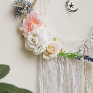 Close-up of bohemian dream catcher with white lace, roses, and silver moon star charms