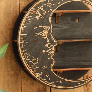 Macro detail of moon-shaped wooden wall shelf featuring celestial face carving and storage