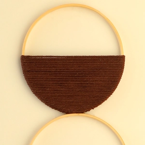 Détail de décoration murale bohème faite main avec anneaux en bois et tissage en coton marron
