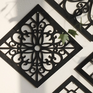 Detailed laser-cut geometric wooden wall decor with matte black finish on a white wall