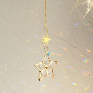 Hanging golden metal star suncatcher with large faceted crystal and rainbow light reflections