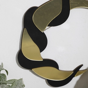 Close-up of bohemian crescent snake wall decor with matte black and gold metal finish