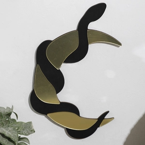 Detail of bohemian crescent snake wall decor with matte black and gold mirror finish