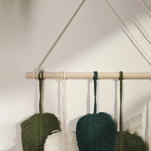 Handwoven Nordic Boho leaf tapestry with white and green cotton feathers on a wood branch