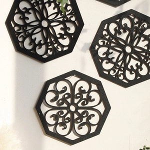 Close-up of black hexagonal carved wall decor with classical symmetrical scroll patterns