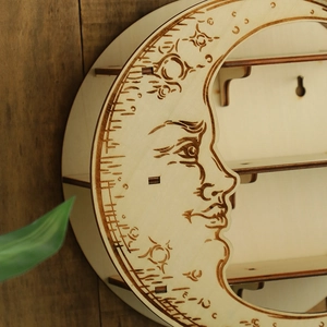 Detail of a round wooden wall shelf featuring laser-engraved crescent moon face pattern