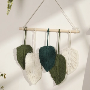 Detailed macro view of handmade macrame leaf wall hanging in forest green and beige tones