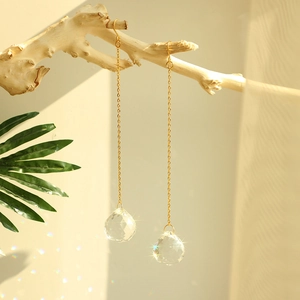 Elegant gold metal chain earrings with faceted crystal ball drops on a natural branch