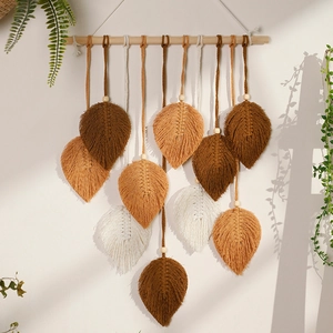 Close-up of bohemian hand-woven cotton leaves hanging on a natural wooden stick