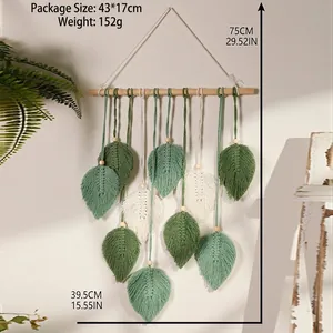 Detail of bohemian woven cotton leaves in green and white hanging on a wood stick