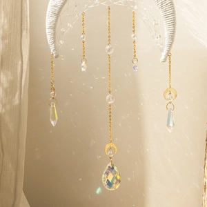 Detail of moon-shaped suncatcher with white woven crescent and hanging crystal teardrops