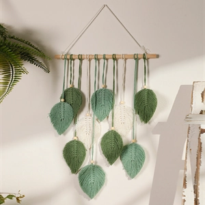 Detailed view of handmade woven macrame leaf tapestry in green and white hanging on wood