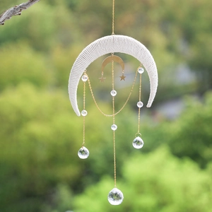 Detailed outdoor view of a crescent moon suncatcher with hanging crystal balls and gold stars
