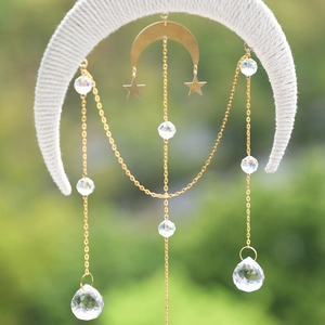 Detail of woven crescent moon suncatcher with golden stars and hanging crystal prisms