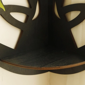 Macro detail of black corner floating shelf with decorative cutout leaf pattern design