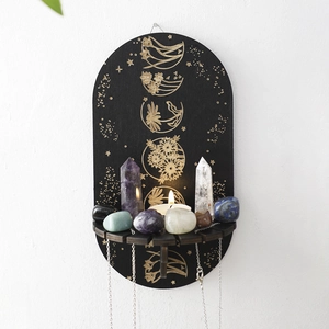 Detail of oval black wooden shelf with golden moon phase patterns and hanging hooks
