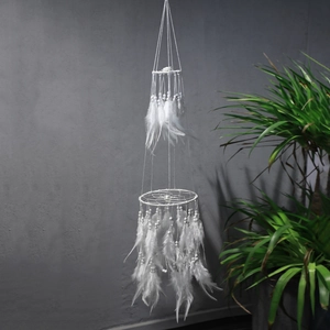 Detail of white double-layer dream catcher with feathers and beads on grey wall