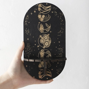 Detail of black moon phase shelf with golden floral etching and wooden texture