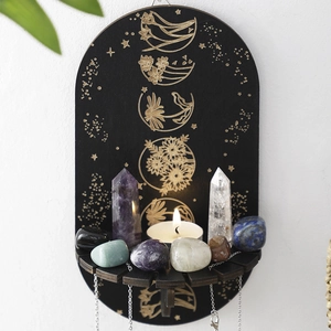 Oval black wooden crystal display shelf with gold floral patterns and glowing candle decor