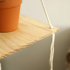 Close-up of handmade bohemian cotton rope knot on natural wood floating shelf texture