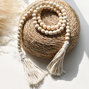 Detail of bohemian wooden bead curtain tieback with white cotton fringe tassels