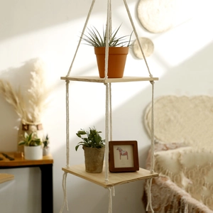 Detail of bohemian handmade cotton rope macrame hanging shelf with natural wood boards