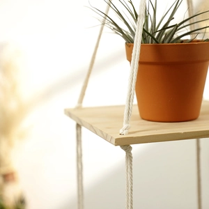 Detail of bohemian handmade cotton rope knot on a multi-layer square wooden floating shelf